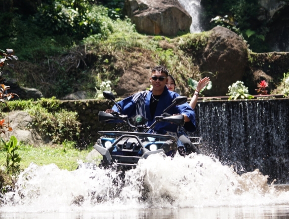 Parade model menggunakan ATV menampilkan busana Batik Kota Batu di area alam Coban Putri, menciptakan konsep fashion show yang unik