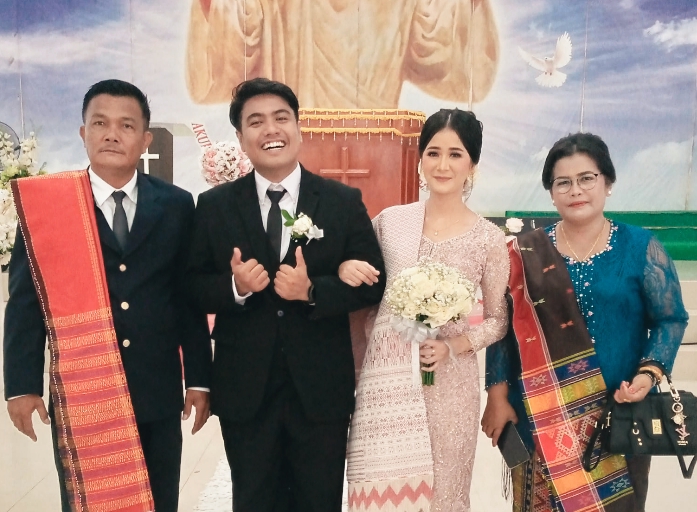 Pasangan pengantin baru Riccy & Kristyani tersenyum bahagia di depan Gereja Pentakosta Sagulung, Batam
