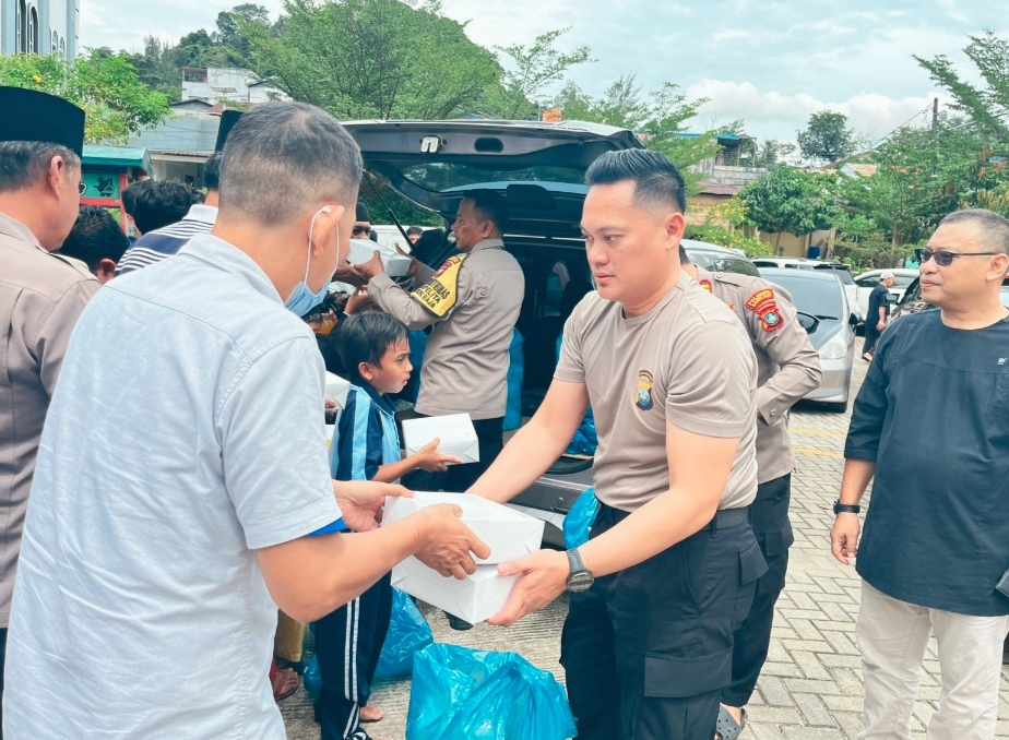 Personel Polsek Lubuk Baja Kompol Rangga Primazada menyerahkan paket bantuan sosial kepada warga Kampung Pelita dalam program Jumat Berkah di Masjid Darul Hikmah.