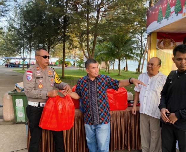 Pendeta Willi menyerahkan nasi kotak kepada Kasat Lantas Polres Natuna IPTU Erwan Toni di Posko Operasi Lilin Seligi, Rabu (24/12/2025).