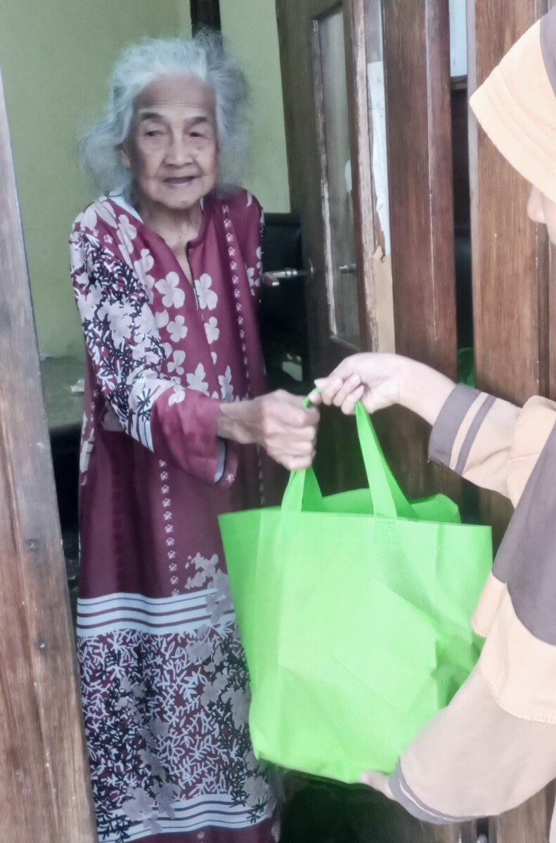 Seorang nenek ketika menerima paket sembako dari siswa siswi MI Miftahul Ulum. 
