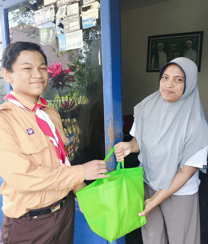 Siswa kelas 6 MI Miftahul Ulum ketika memberikan paket sembako kepada salah satu ibu-ibu keluarga yang membutuhkan warga sekitar lingkungan sekolah. 