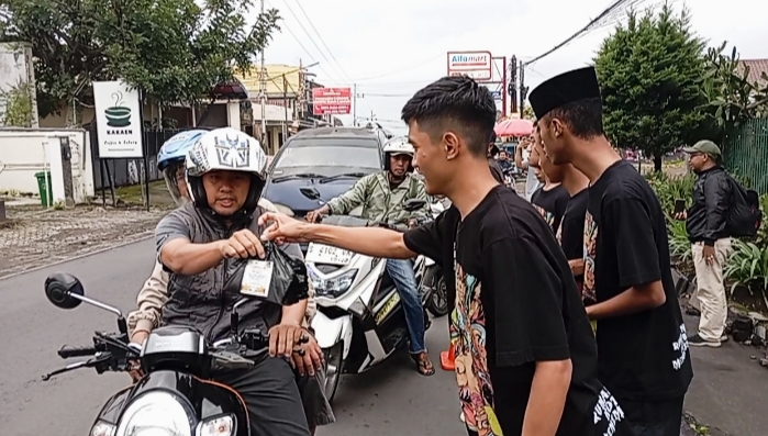 Anggota inklusi Kota Batu dengan semangat membagikan takjil kepada pengguna jalan. 