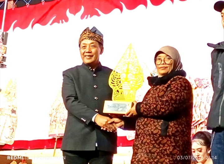 Kepala Desa Sumberbrantas ketika menyerahkan piala kepada salah satu pemenang pawai budaya desa
