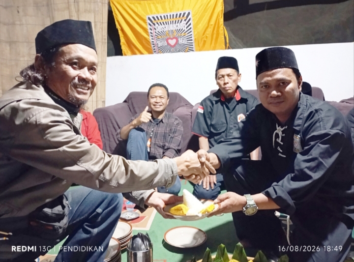 Tampak Anggota Dewan PSHT Cabang Batu memberikan potongan tumpeng kepada Koordinator Kegiatan Kirab Bendera Merah Putih sepanjang 100 meter. 