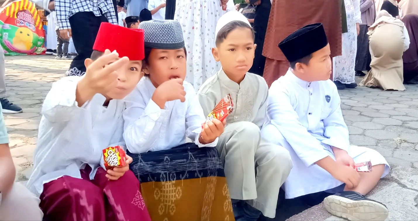 Tampak anak anak yang ceria dan senang duduk bersama sembari menikmati kue.