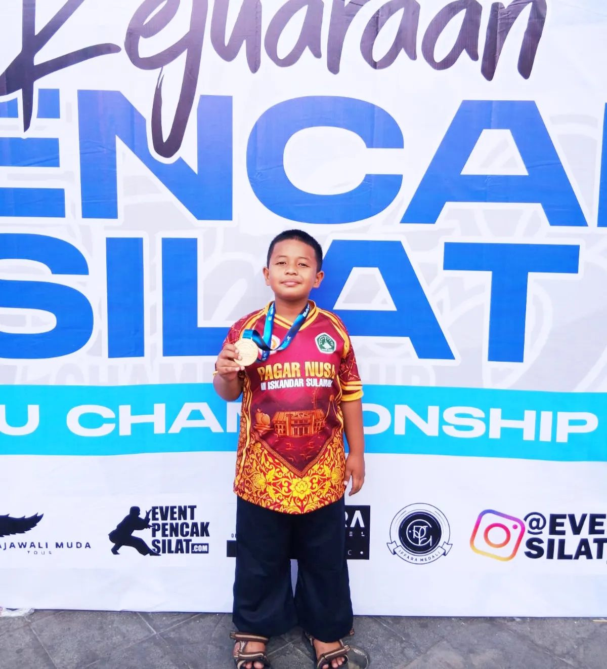 Tampak juga siswa MI Iskandar Sulaiman dengan menunjukan medali yang sudah diperolehnya dalam Kejuaraan Pencak Silat Championship 3 . 